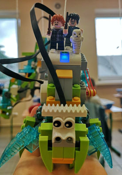 Robot z klocków Lego, przedstawiający bajkowe stworzenie na którym siedzą postaci znane z serii powieści Harry Potter.