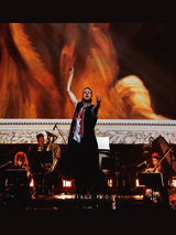 Na zdjęciu orkiestra w trakcie koncertu. Na pierwszym planie dyrygent z uniesioną batutą.