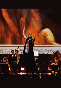 Na zdjęciu orkiestra w trakcie koncertu. Na pierwszym planie dyrygent z uniesioną batutą.