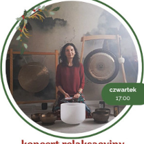 Zdjęcie przedstawia kobietę siedzącą przed dużym gongiem oraz kilkoma misami do śpiewu. Kobieta ma na sobie czerwoną koszulkę, ciemne włosy i patrzy w obiektyw aparatu. Kobieta lekko się uśmiecha.