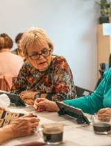 Grupa kobiet gra w Rummikub przy kawie.