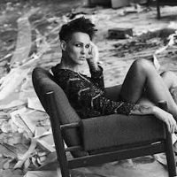 Artystyka siedzi w szpilkach i skuience na krześle, dookoła bałagan "remontowy". Zdjęcie czarno-białe.