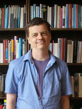 zdjęcie autora w pokoju na tle ściany wypełnionej książkami