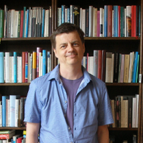 zdjęcie autora w pokoju na tle ściany wypełnionej książkami