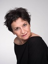 Zdjęcie Danieli Popławskiej w czarnej bluzce na jasno-szarym tle.