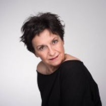 Zdjęcie Danieli Popławskiej w czarnej bluzce na jasno-szarym tle.