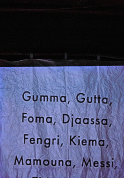 .Pognieciona kartka paperu, na której napisanych jest kilka słów, np. Gumma, Gutta, Foma. Czarne tło.