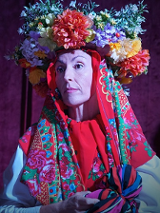 Zdjęcie kobiety w kolorowej chuście i wianku na głowie.