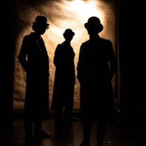 Zarys trzech postaci, za nimi jasna poświata.