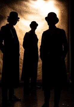 Zarys trzech postaci, za nimi jasna poświata.