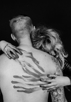 Czarno-białe zdjęcie kobiety obejmującej mężczyznę, twarze kobiety i mężczyzny są niewidoczne.