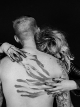 Czarno-białe zdjęcie kobiety obejmującej mężczyznę, twarze kobiety i mężczyzny są niewidoczne.