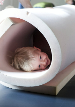 Zdjęcie uśmiechniętego dziecka w tubie z gąbki.