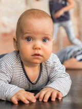 Zdjęcie niemowlaka leżacego na brzuchu i podpierającego się rączkami
