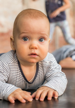 Zdjęcie niemowlaka leżacego na brzuchu i podpierającego się rączkami