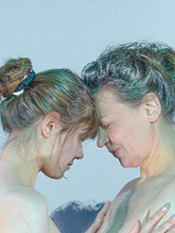 Dwie kobiety, młodsza i starsza, naprzeciwko siebie, dotykają się czołami.