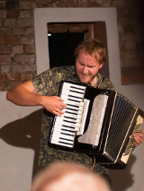 Na zdjęciu mężczyzna grający na akordeonie.