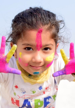 Dziewczynka z pomalowanymi rękoma i tawrzą kolorowymi farabami.