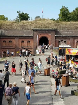Ludzie chodzący po terenir fortu pomiędzy budkami z jedzeniem, straganami i innymi atrakacjami.