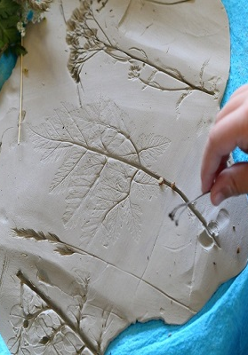 Kawałek gliny, w którym są odciśnięte liście.