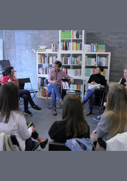 Zdjęcie ze spotkania Zamkowego Klubu Książki Ukraińskiej. Uczestnicy siedzą na krzesłach ustawionych w kształcie koła. W tle wypełnione książkami regały Księgarni Bookowski.