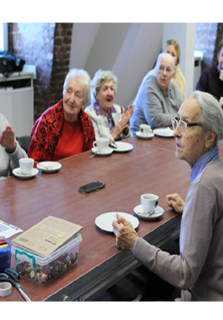 Uczestnicy warsztatów siedzą przy brązowym stole, na którym leżą kolorowe flamastry i pudełko z guzikami