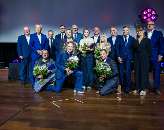 Zdjęcie grupowe uhonorowanych nagrodami na środku sceny.