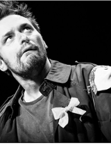 czarno - białe zdjecie przedstawia mężczyznę, który lekko przechylony w prawo, zdziwiony patrzy w górę z zadartą głową