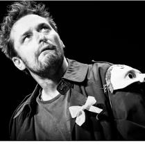 czarno - białe zdjecie przedstawia mężczyznę, który lekko przechylony w prawo, zdziwiony patrzy w górę z zadartą głową