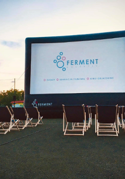 Duży ekran do wyświetlania filmów, a przed nim leżaki