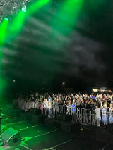 Mężczyzna na scenie w zielnym świetle, przed nimi publiczność.