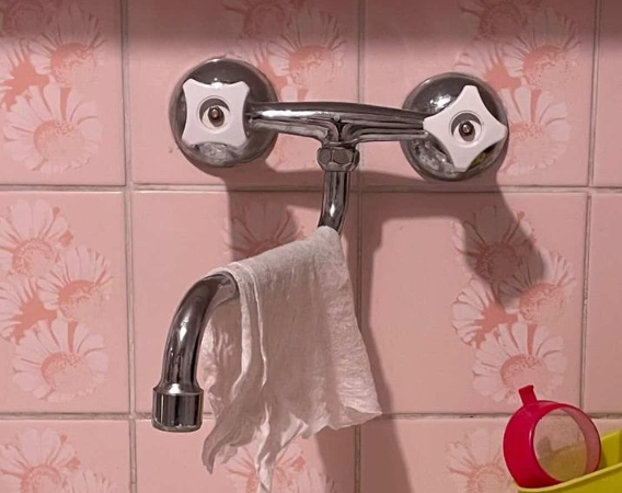 Zdjęcie kuchennego zlewu z metalowym kranem i wiszącą na nim ścierką.