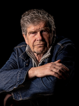 Zdjęcie Lecha Dyblika, który patrzy na wprost, ciemne tło.