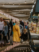 Ludzie chodzący pod zadaszonymi straganami.