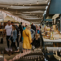 Ludzie chodzący pod zadaszonymi straganami.