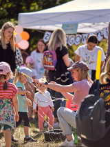 Zdjcie przedstawia grupę dzieci, ktore przyglądają się pani robiącej bańki mydlane.