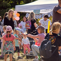 Zdjcie przedstawia grupę dzieci, ktore przyglądają się pani robiącej bańki mydlane.