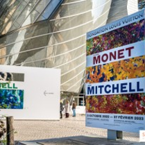 Przed wejściem reklmay o wystawie w środku muzeum. W tle nowoczesne przeszkolne wejście do muzeum.