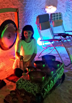 Zdjęcie przedstawia kobietę grającą na misach w grocie solnej.