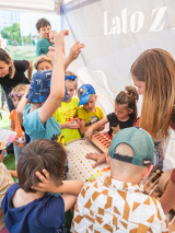 Na zdjęciu znajduje się grupa dzieci, która bawi się przy zabawce.