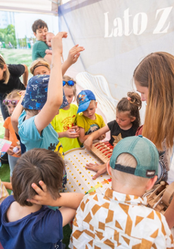 Na zdjęciu znajduje się grupa dzieci, która bawi się przy zabawce.