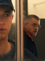 Zdjęcie mężczyzny, który w odbiciu w lustrze widzi innego mężczyznę, który na niego patrzy.