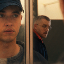 Zdjęcie mężczyzny, który w odbiciu w lustrze widzi innego mężczyznę, który na niego patrzy.