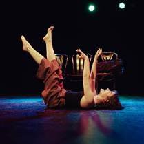 Na podłodze leżu kobieta, ma uniesione do góry ręce i nogi.