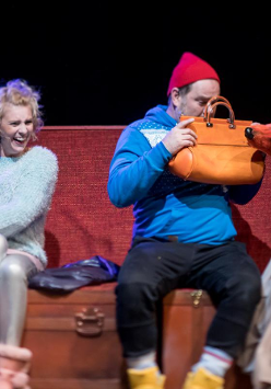 Zdjęcie ze spektaklu: trzy osoby siedzące na ławce. Mężczyzna trzyma przed sobą torebkę, zasłania się przed psem animowanym przez jedną z dwóch aktorek.