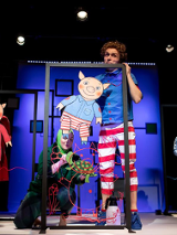 Zdjęcie przedstawiające aktorów na scenie z lalkami bohaterów przedstawienia.