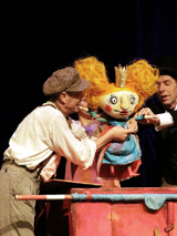Zdjęcie aktorów z lalką w trakcie spektaklu.