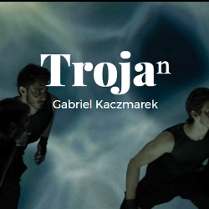 zdjęcie przedstawia dwie postaci w ruchu, pochylone, ubrane na czarno, pośrodku biały napis Trojan, poniżej Gabriel Kaczmarek