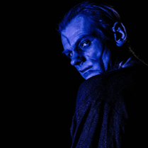 Zdjęcie mężczyzny oglądającego się przez ramię, jego twarz oświetla niebieskie światło.