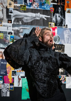 Zdjęcie mężczyzny w czarnym stroju na tle kolorowych zdjęć.